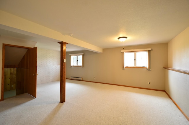 basement featuring a baseboard heating unit, brick wall, light colored carpet, and a healthy amount of sunlight