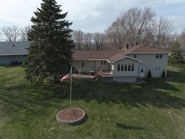 rear view of house featuring a chimney, a wooden deck, and a yard