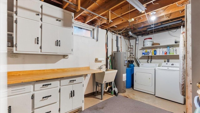 laundry area featuring water heater, independent washer and dryer, a sink, and cabinet space