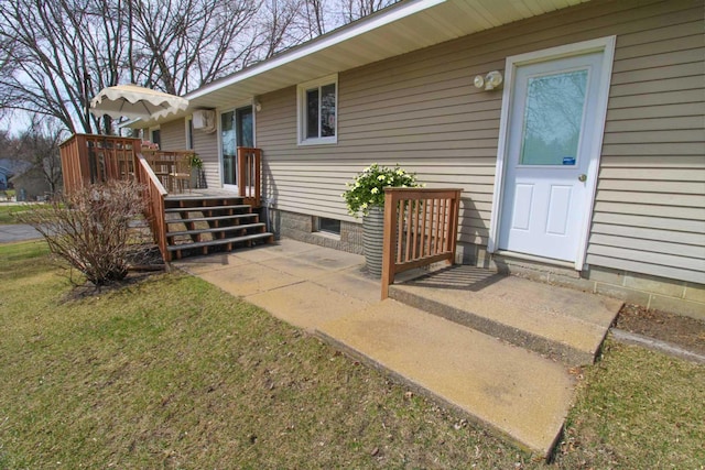 view of exterior entry with a wooden deck and a yard