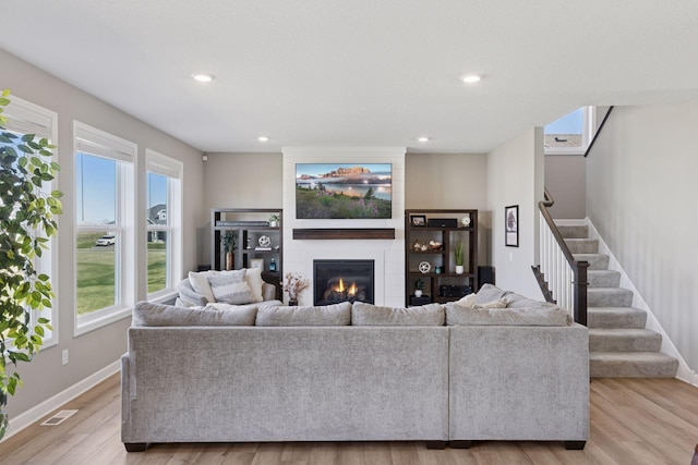 2141 Johanna Cir, Lino Lakes, MN 55038 - living room featuring stairway, light wood-style floors, a fireplace, and a wealth of natural light