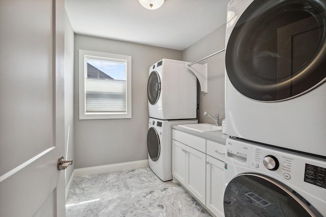 4233 Halstead Bay Alcove, Minnetrista, MN 55331 - laundry area featuring stacked washing machine and dryer, cabinet space, light marble finish floors, and baseboards