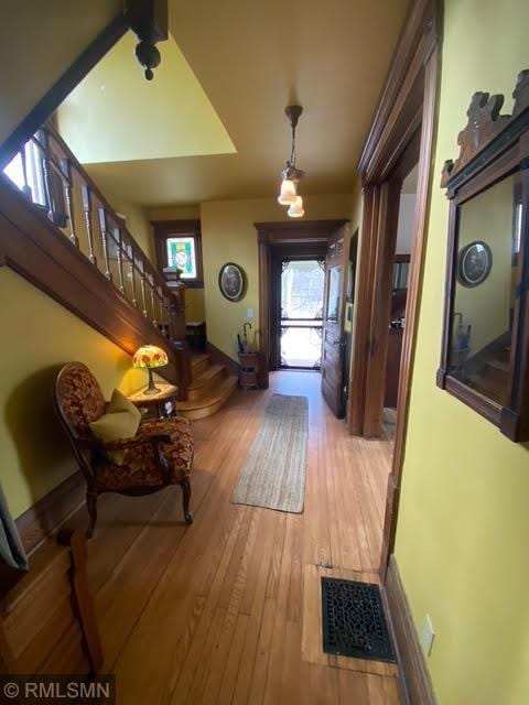 foyer entrance with hardwood / wood-style floors, plenty of natural light, visible vents, and stairway