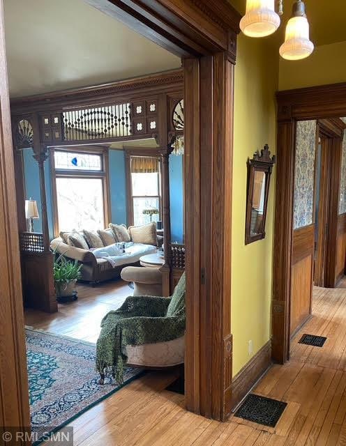 hallway with baseboards, hardwood / wood-style floors, and visible vents