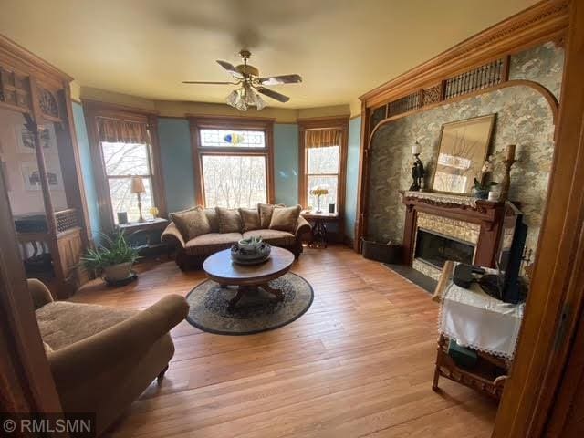 living area featuring wood finished floors, a fireplace, and ceiling fan