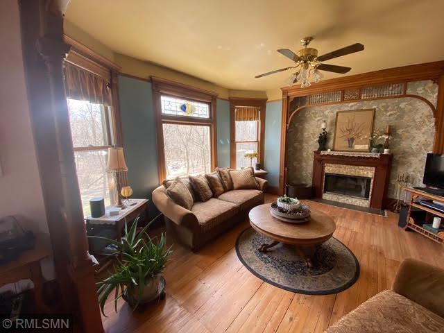 living room featuring hardwood / wood-style flooring, ceiling fan, and a glass covered fireplace