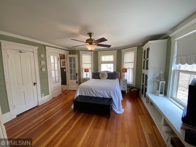 bedroom with a ceiling fan, wood finished floors, and ornamental molding