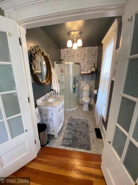 bathroom featuring a shower stall, toilet, vanity, and wood finished floors