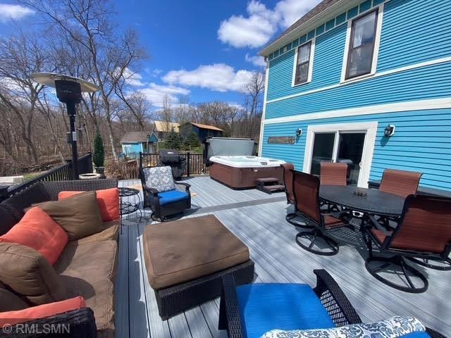 wooden deck with a hot tub and outdoor dining space