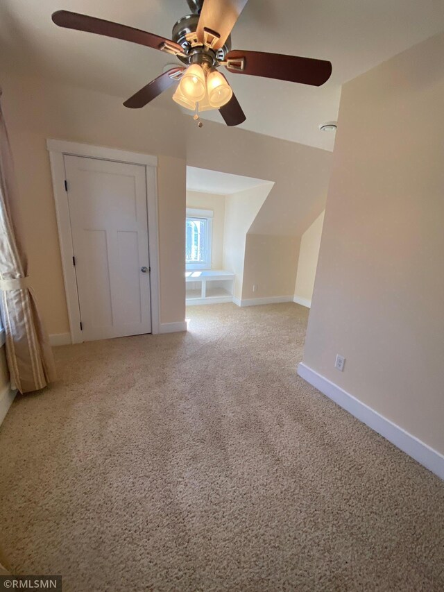 bonus room with light carpet, a ceiling fan, and baseboards