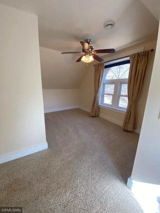 additional living space with carpet flooring, vaulted ceiling, visible vents, baseboards, and a ceiling fan