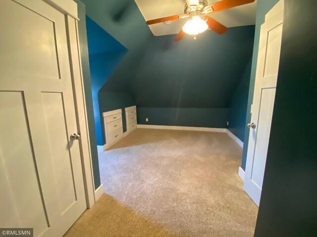 additional living space featuring baseboards, lofted ceiling, a ceiling fan, and carpet