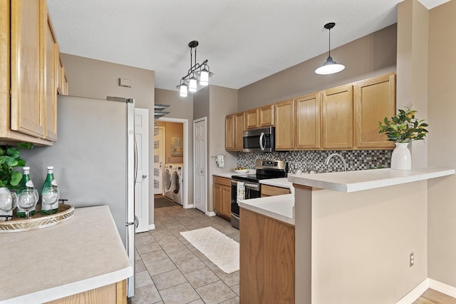 7619 Derby Ln, Shakopee, MN 55379 - kitchen with stainless steel appliances, separate washer and dryer, a peninsula, tasteful backsplash, and light countertops