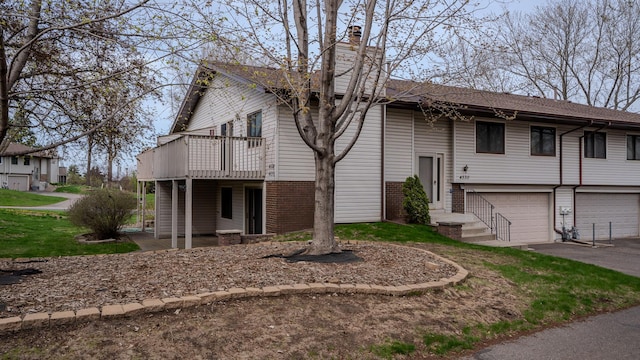 view of front of house featuring an attached garage, brick siding, aphalt driveway, and a chimney