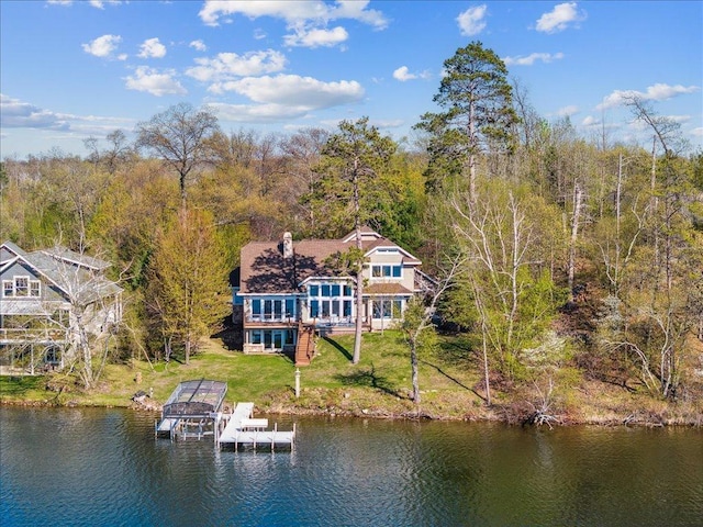 back of property featuring a yard, a water view, a view of trees, and a balcony