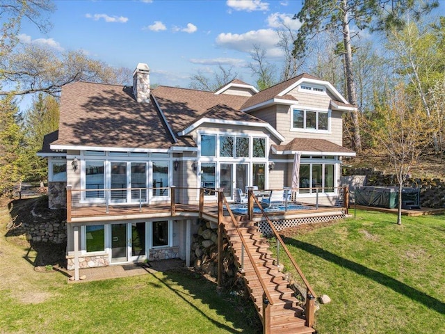 rear view of house featuring stone siding, a wooden deck, a yard, stairs, and roof with shingles