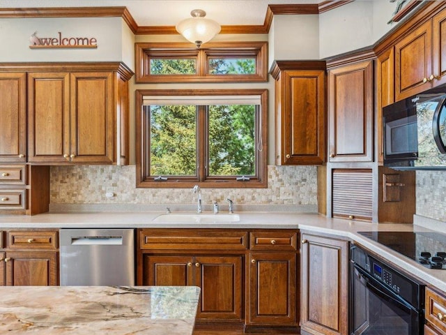 kitchen featuring black appliances, a sink, ornamental molding, and light countertops
