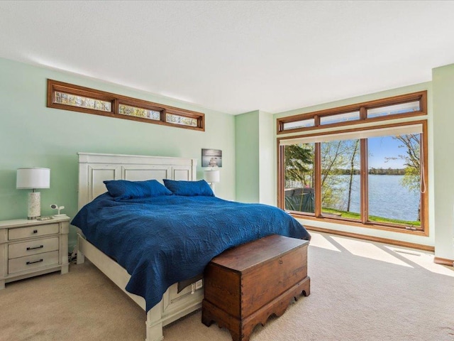 bedroom featuring light carpet and a water view