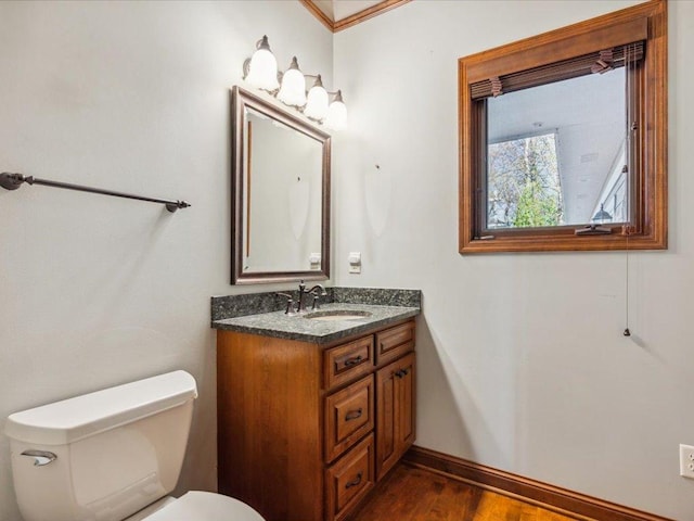 half bath with baseboards, toilet, vanity, and wood finished floors