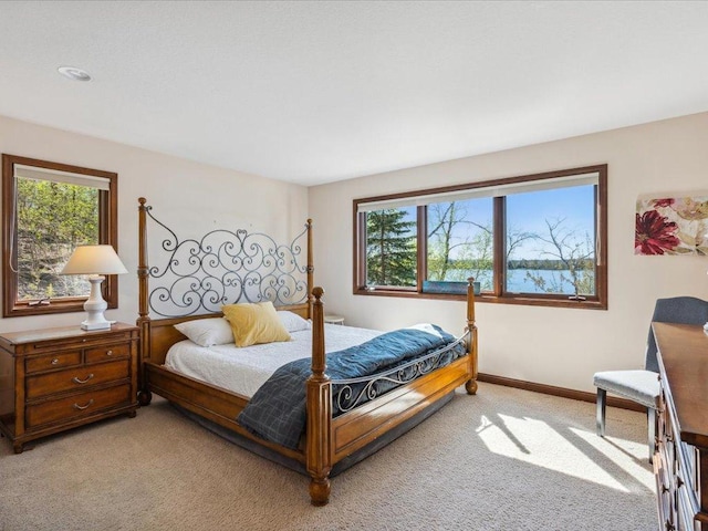 bedroom with light colored carpet, multiple windows, and baseboards