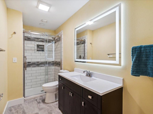bathroom featuring a shower stall, toilet, vanity, and baseboards