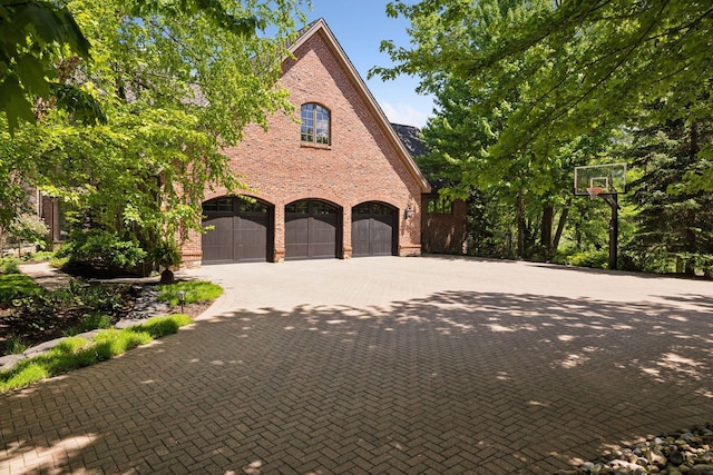 614 Hidden Creek Trl, Mendota Heights, MN 55118 - view of side of home featuring brick siding, decorative driveway, and an attached garage