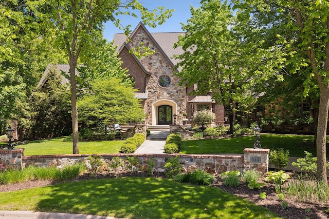 614 Hidden Creek Trl, Mendota Heights, MN 55118 - tudor house with french doors, a standing seam roof, stone siding, and a front lawn