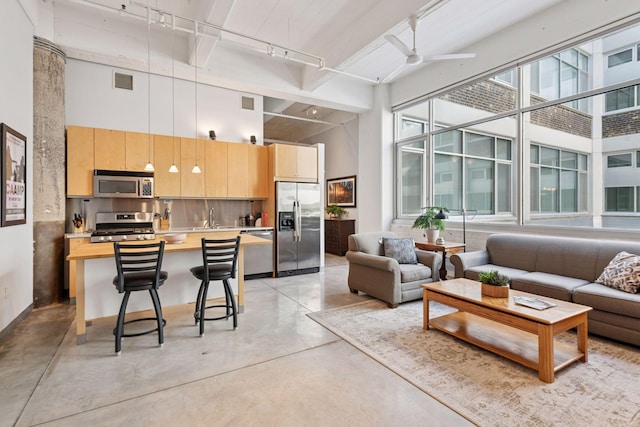 living area featuring track lighting, finished concrete flooring, a towering ceiling, and a ceiling fan
