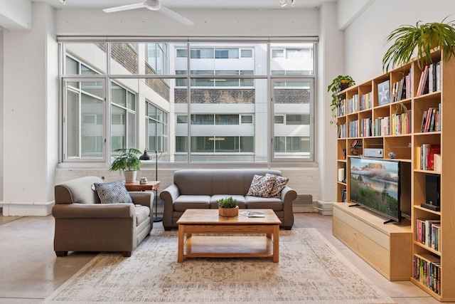 living room featuring healthy amount of natural light, a ceiling fan, and concrete flooring