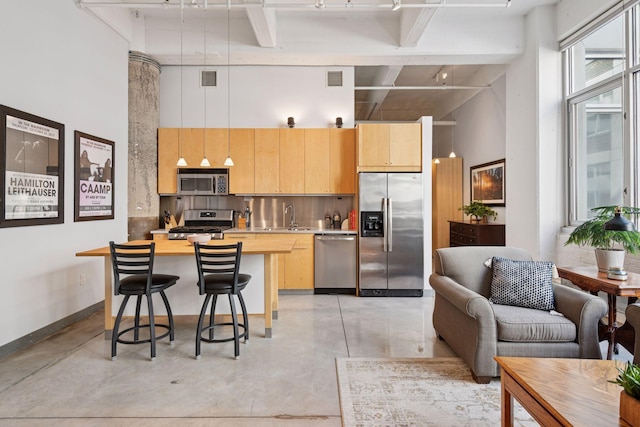 kitchen featuring appliances with stainless steel finishes, a towering ceiling, concrete flooring, a kitchen breakfast bar, and butcher block countertops