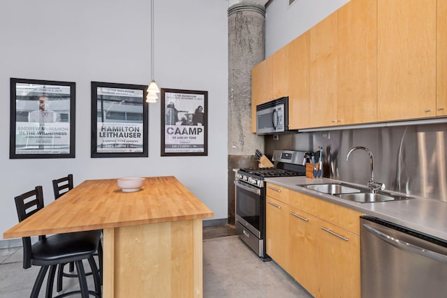 kitchen with appliances with stainless steel finishes, a sink, wooden counters, a breakfast bar area, and finished concrete flooring