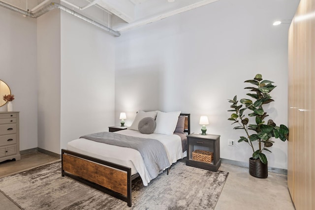 bedroom with concrete floors and baseboards