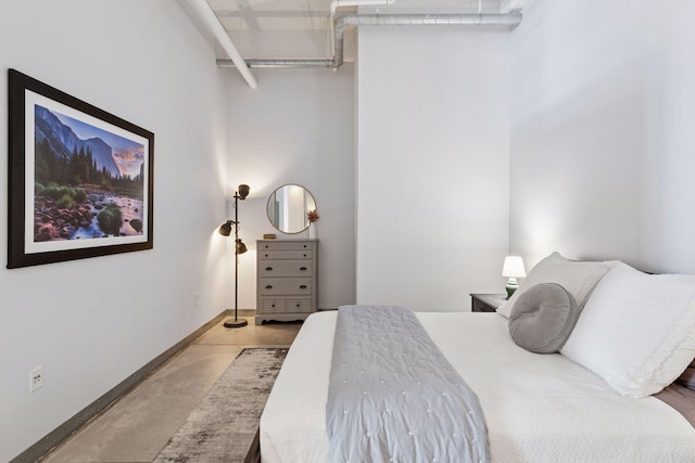 bedroom with concrete flooring and baseboards