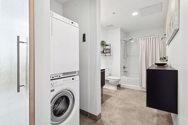 washroom featuring estacked washer and dryer, baseboards, and attic access