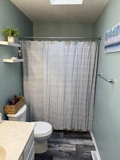 1415 Trailwood Ln SW, Faribault, MN 55021 - bathroom featuring vanity, toilet, curtained shower, a textured ceiling, and wood finished floors
