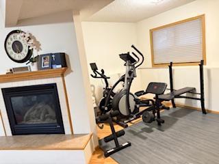 1415 Trailwood Ln SW, Faribault, MN 55021 - workout room featuring a glass covered fireplace, wood finished floors, and baseboards