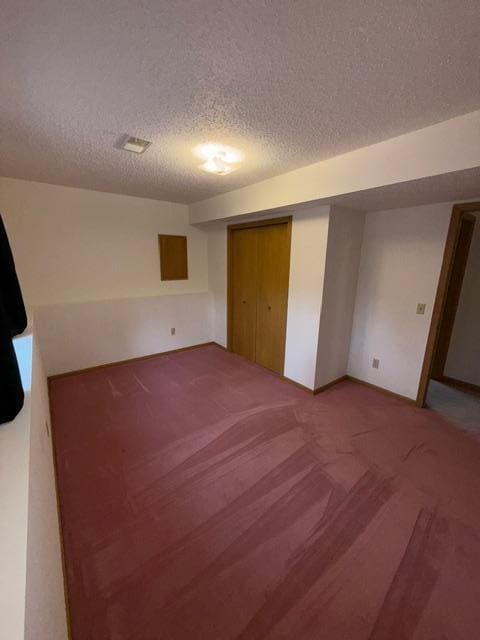 1415 Trailwood Ln SW, Faribault, MN 55021 - unfurnished bedroom featuring a textured ceiling, carpet floors, baseboards, and a closet