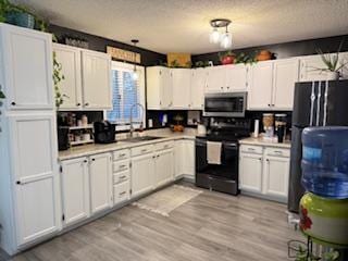 1415 Trailwood Ln SW, Faribault, MN 55021 - kitchen with black appliances, a sink, white cabinets, light countertops, and a textured ceiling
