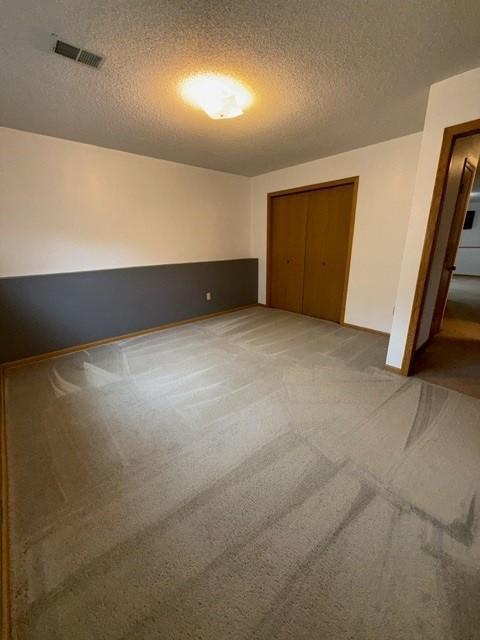 1415 Trailwood Ln SW, Faribault, MN 55021 - unfurnished bedroom with a textured ceiling, light colored carpet, a closet, and baseboards