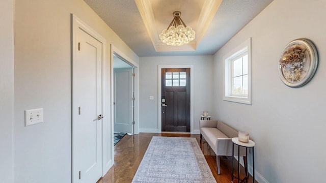 entrance foyer with baseboards, a tray ceiling, a notable chandelier, and dark wood-style floors
