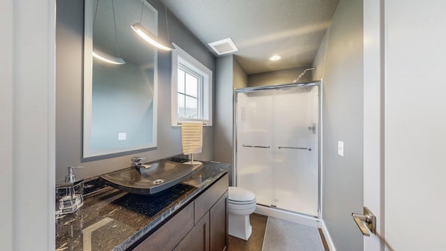 bathroom featuring vanity, baseboards, a stall shower, and toilet
