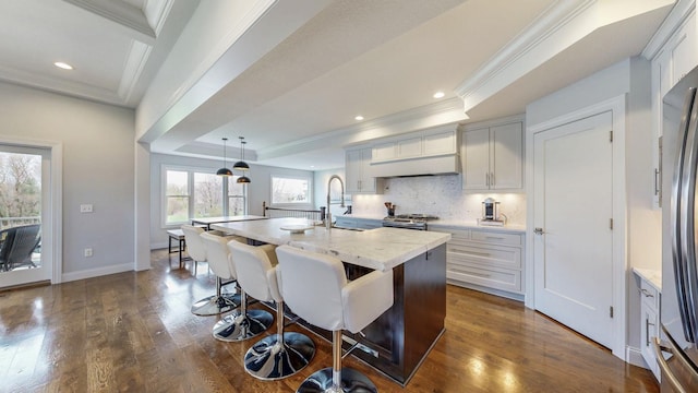 kitchen featuring a kitchen breakfast bar, ornamental molding, dark wood-style floors, and a sink