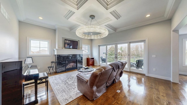 living area featuring baseboards, a fireplace, coffered ceiling, and wood finished floors