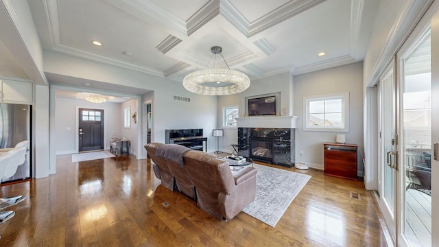living room with a chandelier, wood finished floors, visible vents, and a fireplace