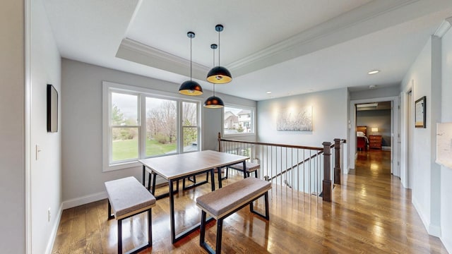 dining room with baseboards, ornamental molding, wood finished floors, and a tray ceiling