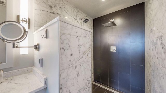 bathroom with visible vents, a tile shower, and tile walls