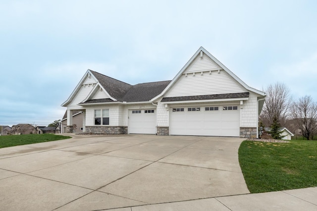craftsman-style home featuring a shingled roof, a front lawn, stone siding, a garage, and concrete driveway