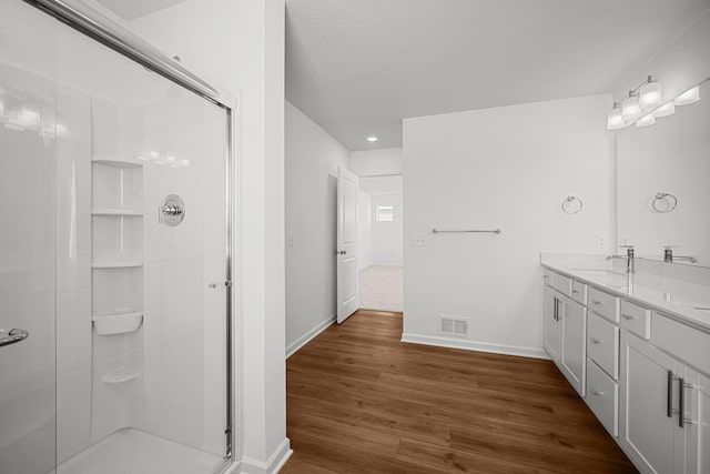 bathroom with wood finished floors, visible vents, double vanity, and a stall shower
