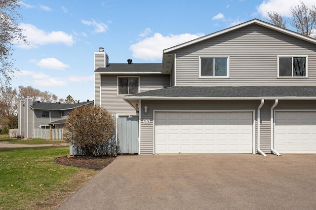 view of front of home with a chimney, an attached garage, a shingled roof, a front yard, and aphalt driveway