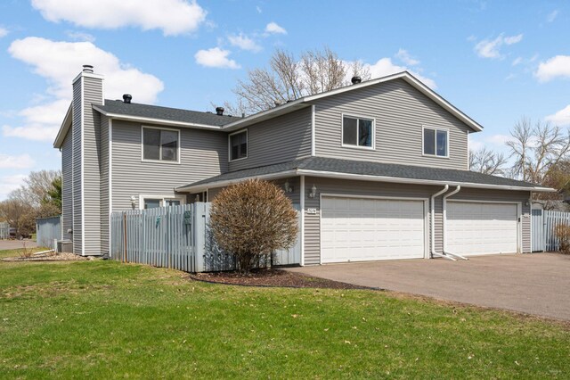 view of front of property with a chimney, a front lawn, aphalt driveway, an attached garage, and fence